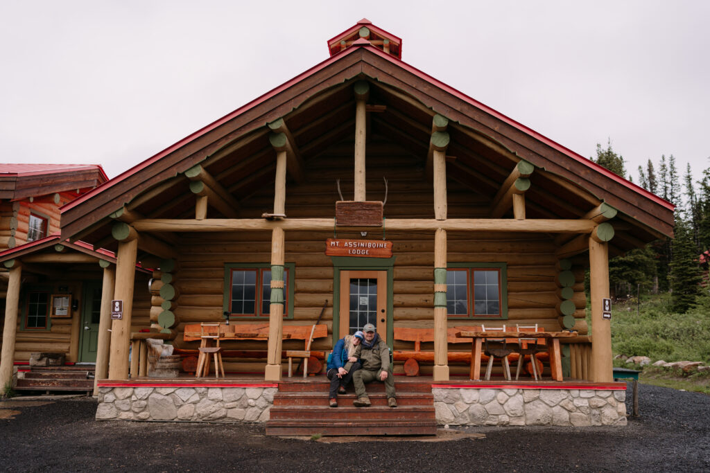 Couple sits on deck in front of Mount Assiniboine Lodge during elopement