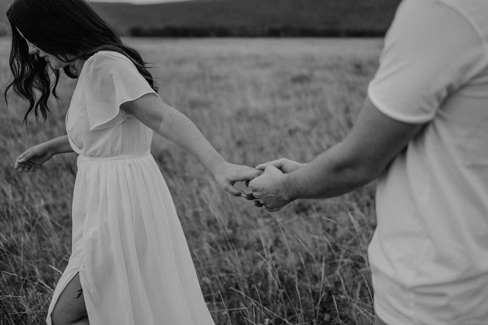 Couple holds hands in field after a Waterton elopement. 