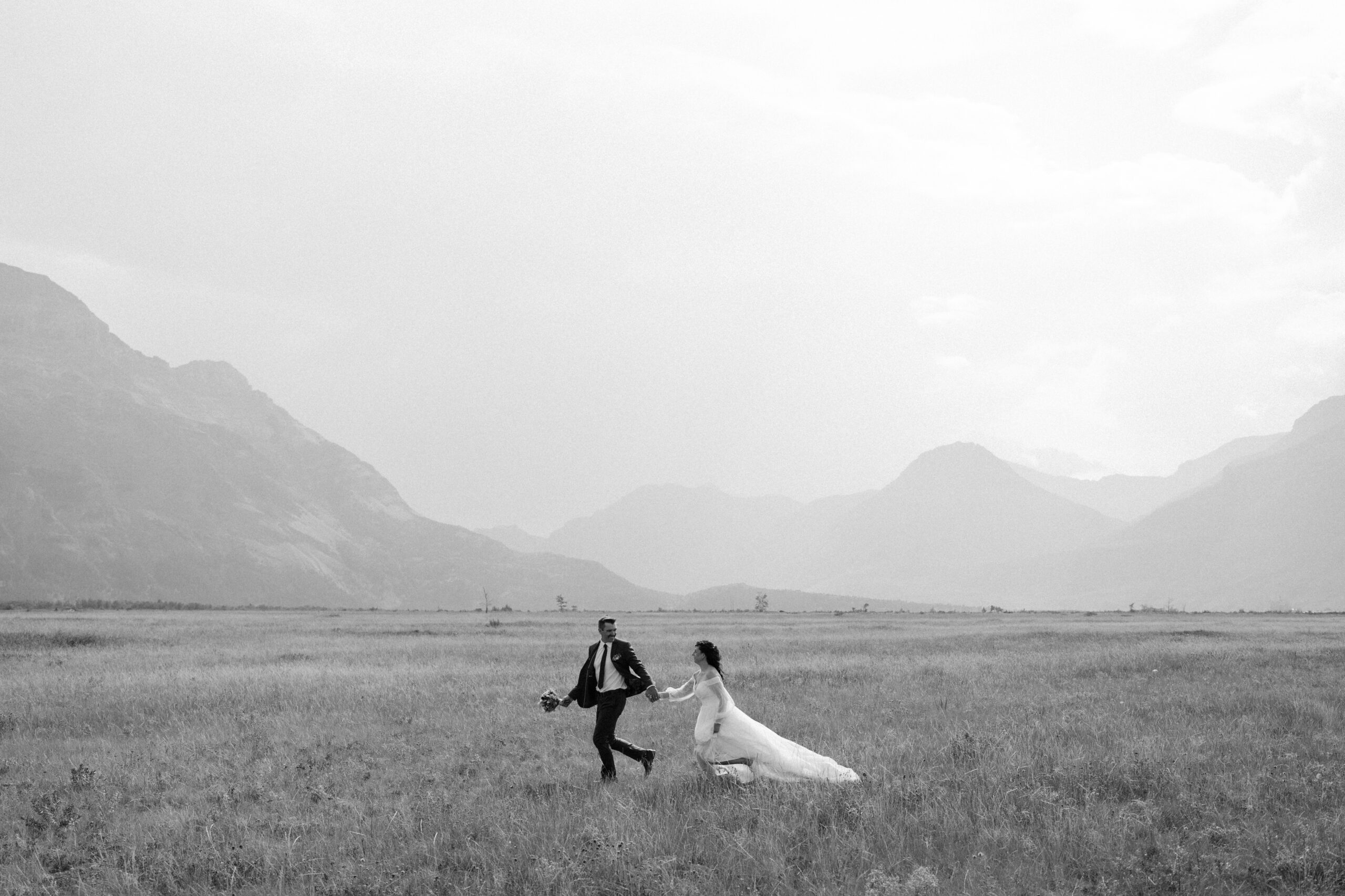 couple runs through field during waterton elopement