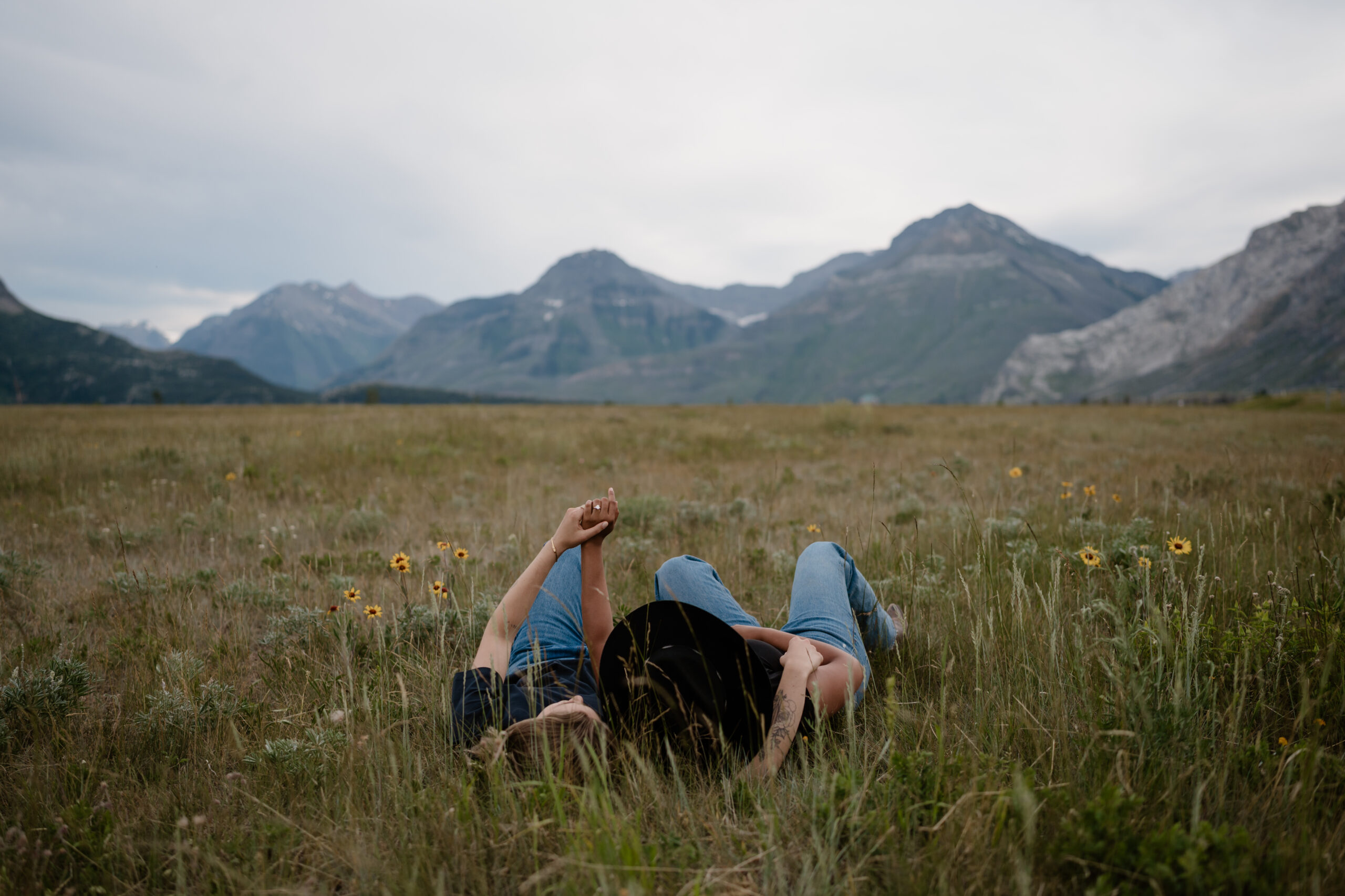 couple lays in grass in waterton lakes national park