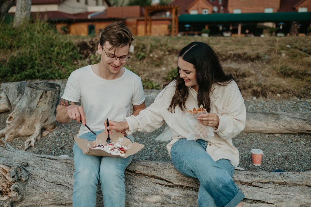 Couple sits on log in Wateron eating waffles from Waffleton