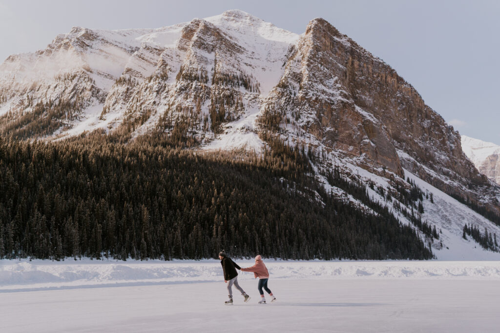 couple skates on lake louise at sunrise after banff proposal