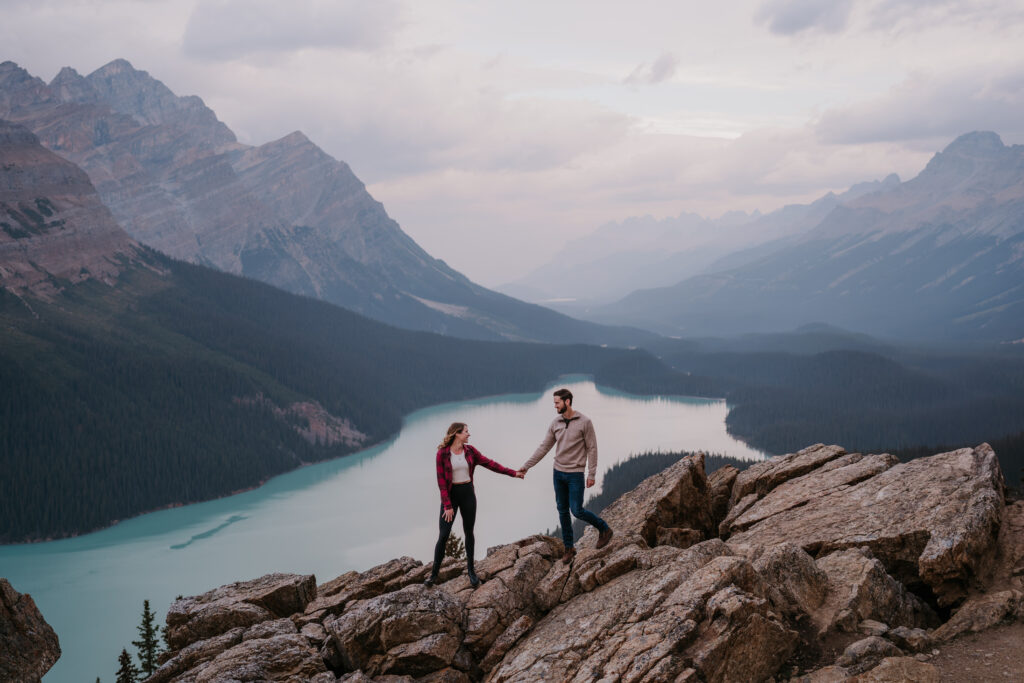 couple holds hands looking at each other at peyto lake in banff 