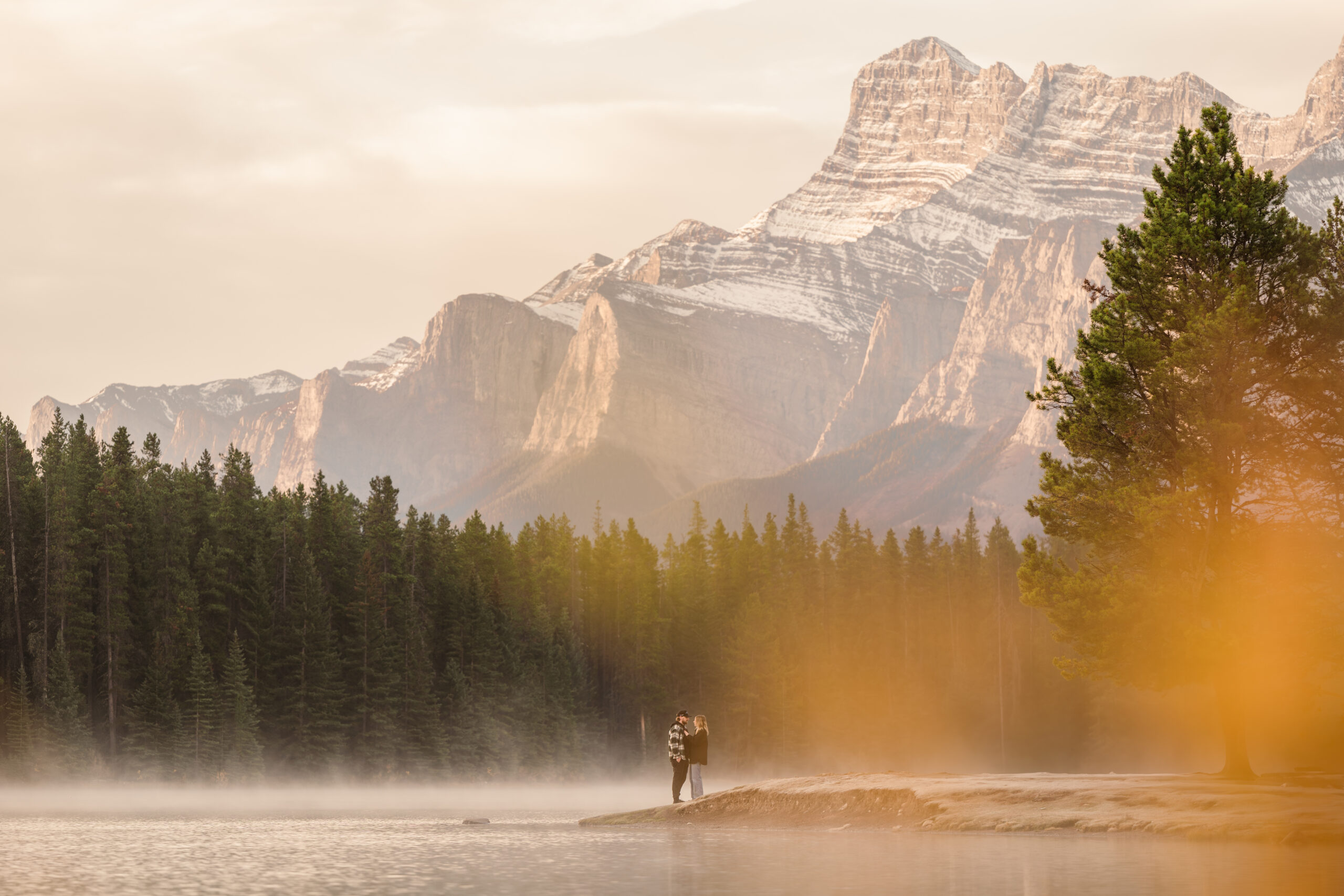 couple hugs at two jack lake in the fall during banff engagement
