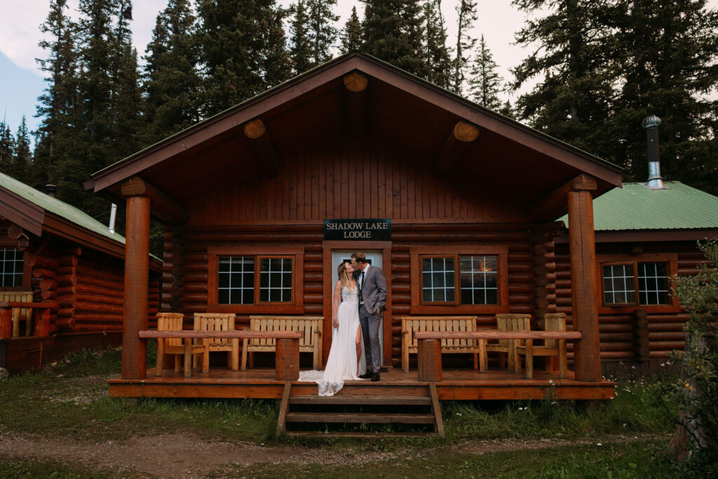 Couple kisses on porch of Shadow Lake Lodge during elopement