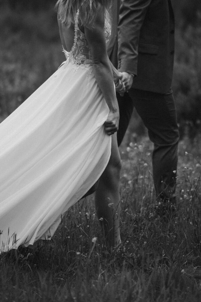 couple walks barefoot through grass at shadow lake lodge during elopement