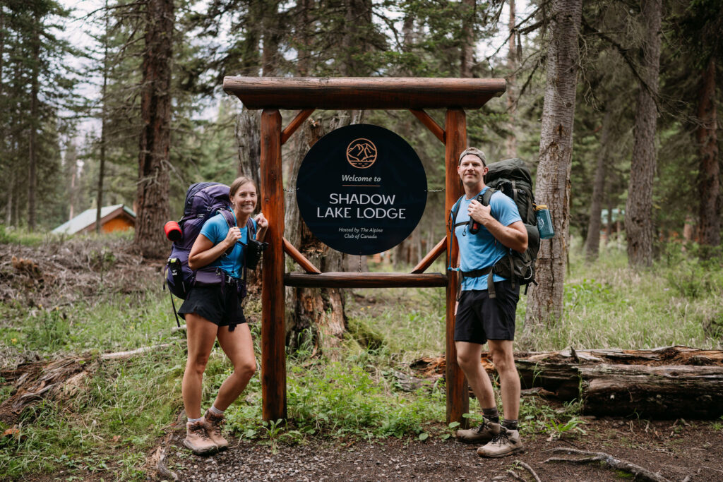 Couple stands in front of Shadow Lake Lodge sign