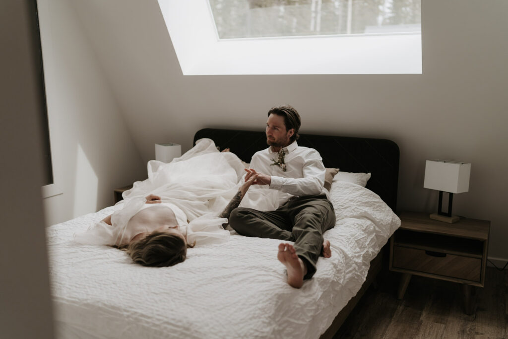 bride and groom cuddle on bed during nordegg cabin elopement