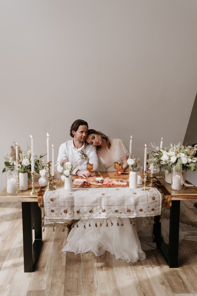 bride rests head on grooms shoulder during cabin elopement with candlelit dinner set up in front of them