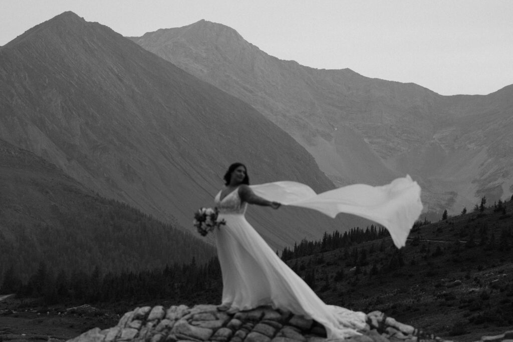 black and white photo of bride with her cape blowing behind her 