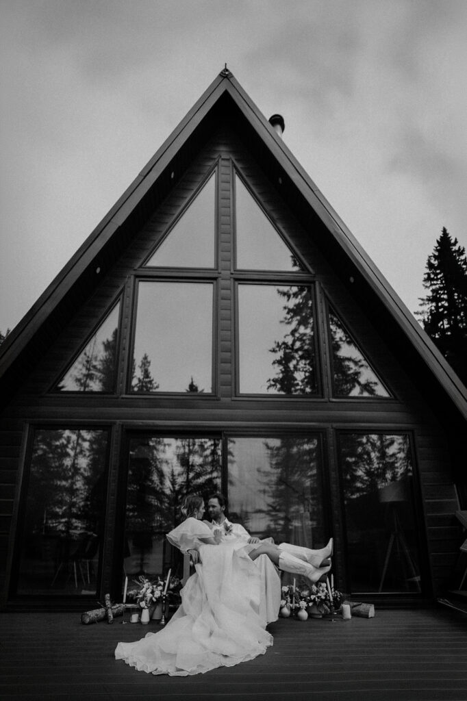 bride and groom sit together on deck of A-Frame during a cabin elopement