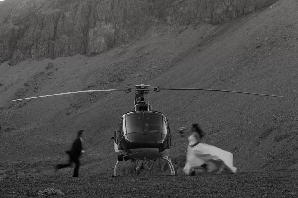 brides run towards each other in front of helicopter during nordegg elopement