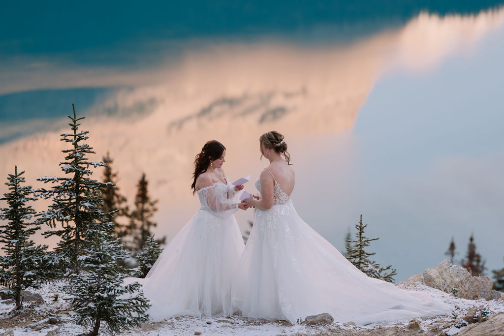 two brides exchange vows in snowy peyto lake ceremony with alpenglow in the background of the lake
