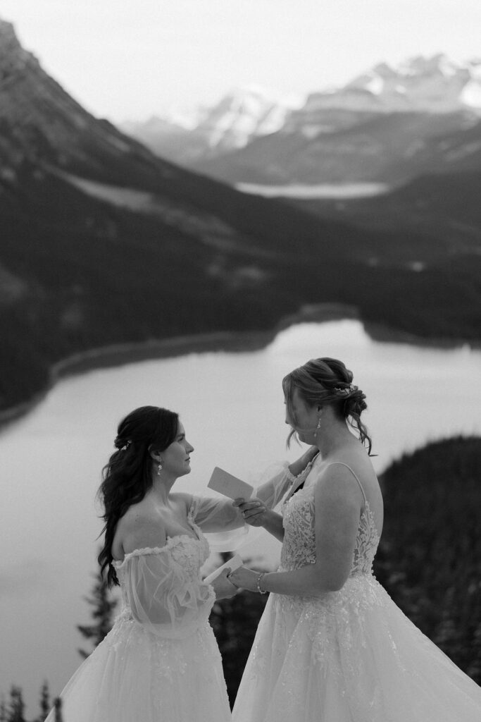 bride reaches up and has hand on other brides shoulder as they exchange vows