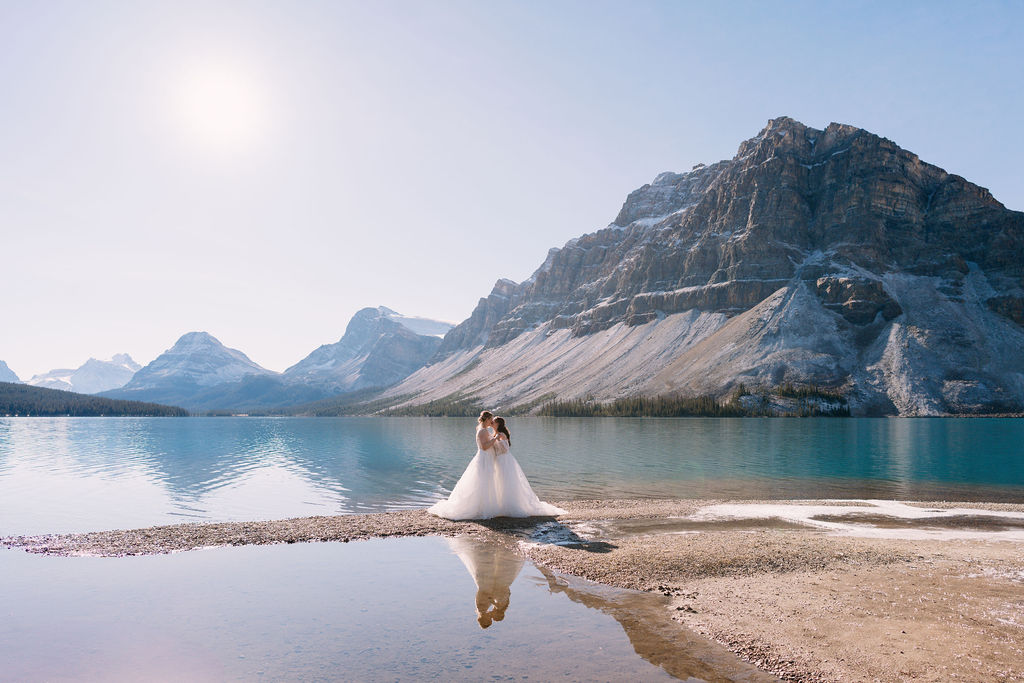 brides kiss with their reflection showing at Bow Lake