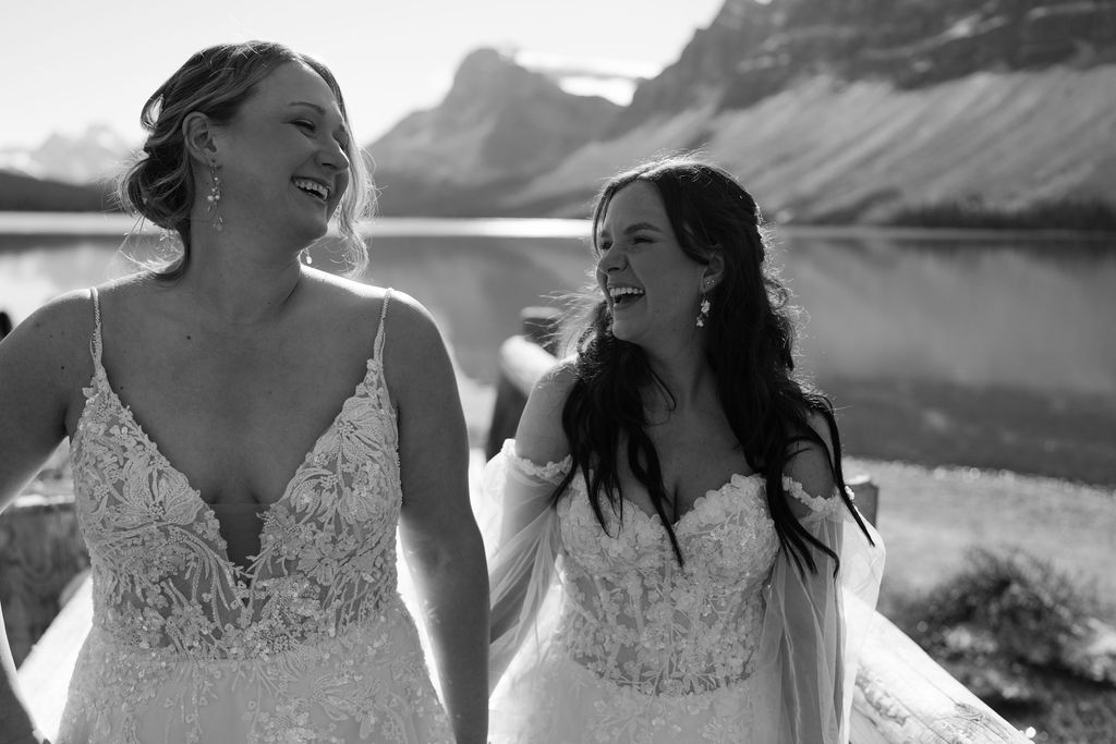 Bride laugh while walking along the bridge at Bow Lake