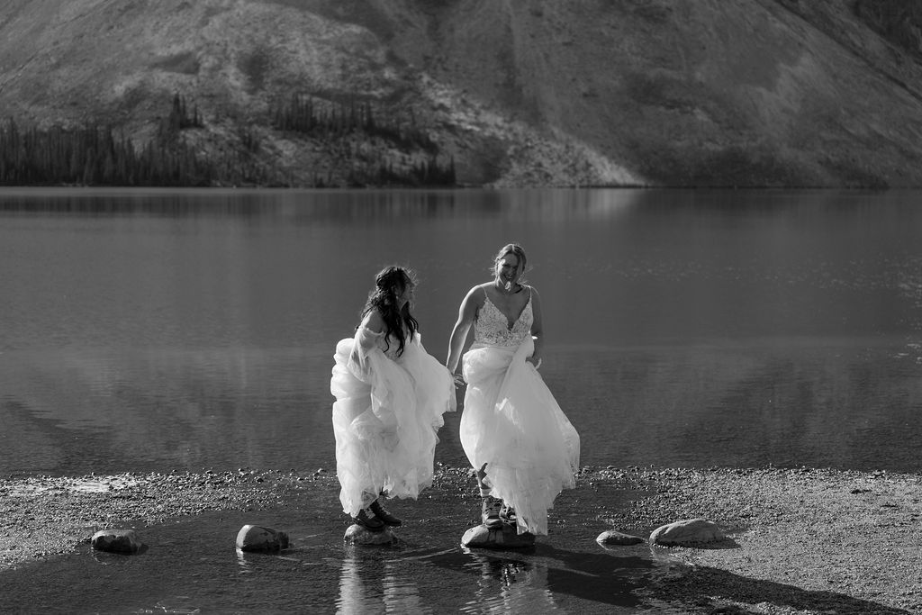 Brides hop over rock at Bow Lake