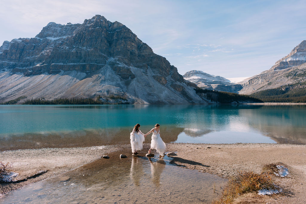 Bride leads wife over rocks at Bow Lake