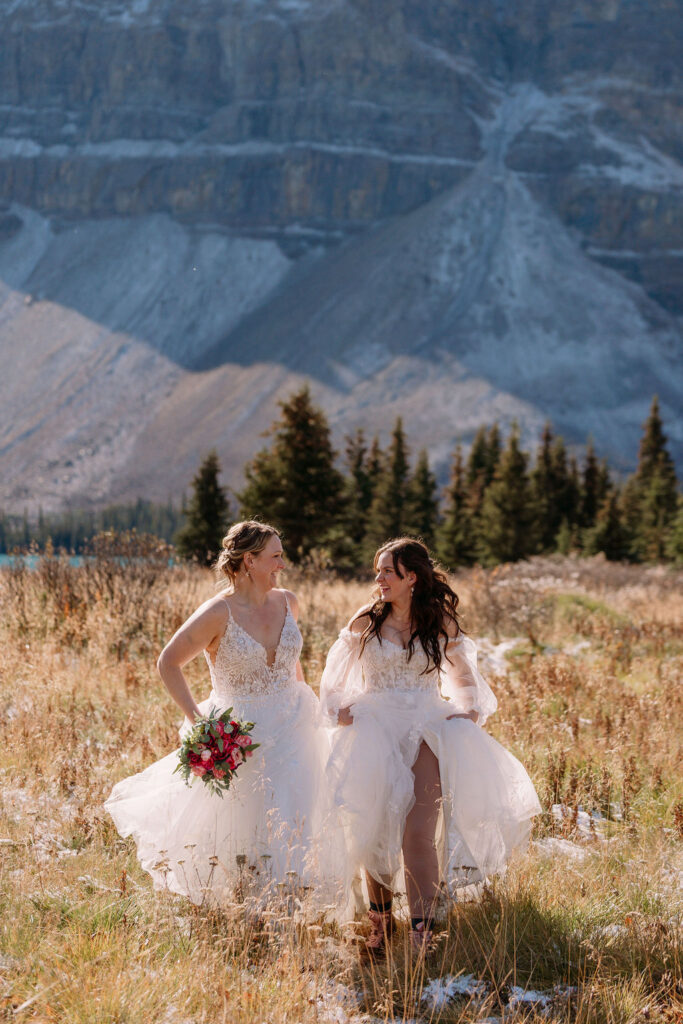 Brides run through field at Bow Lake