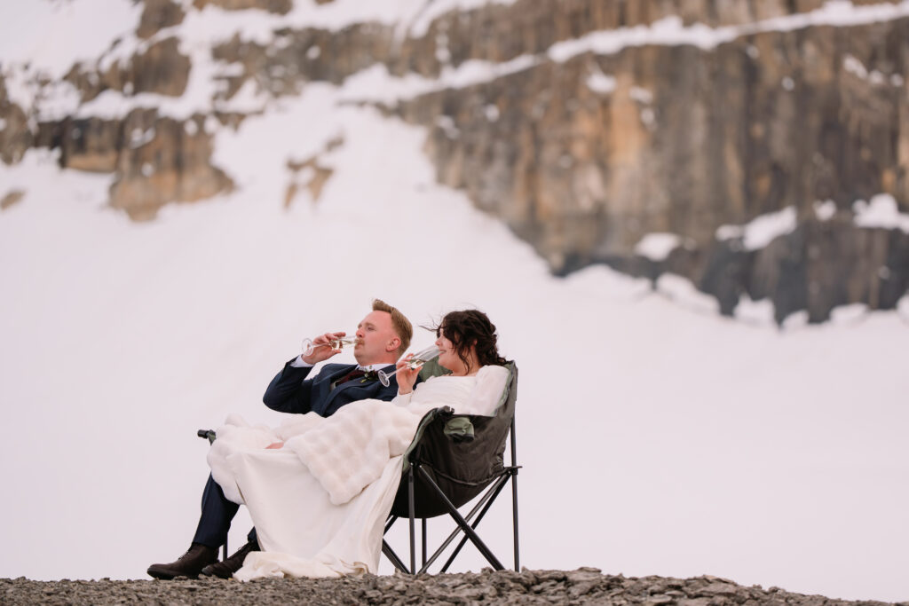 couple sits in kuma chair drinking champagne during helicopter elopement 
